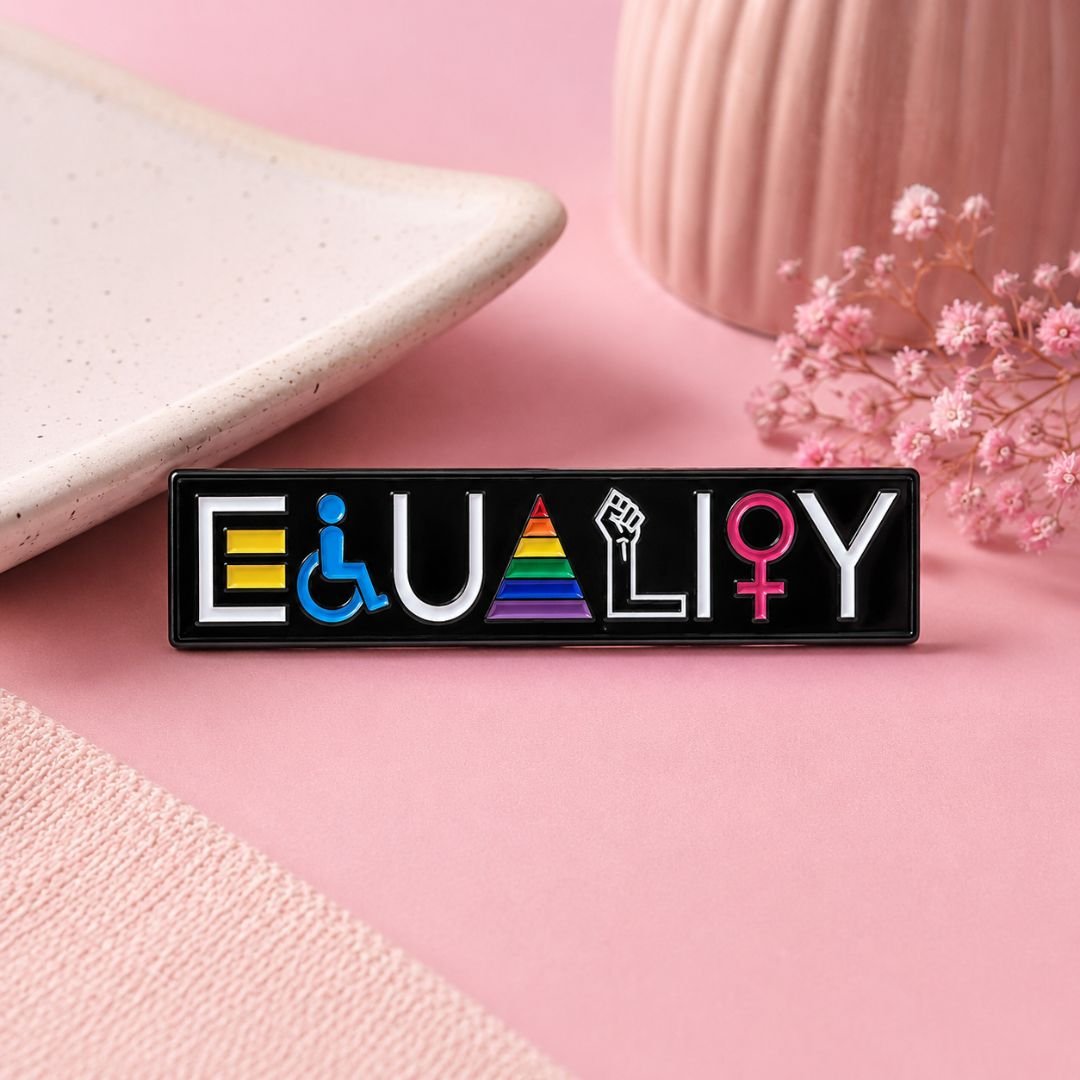 Equality enamel pin with colourful lettering on a black rectangular background.