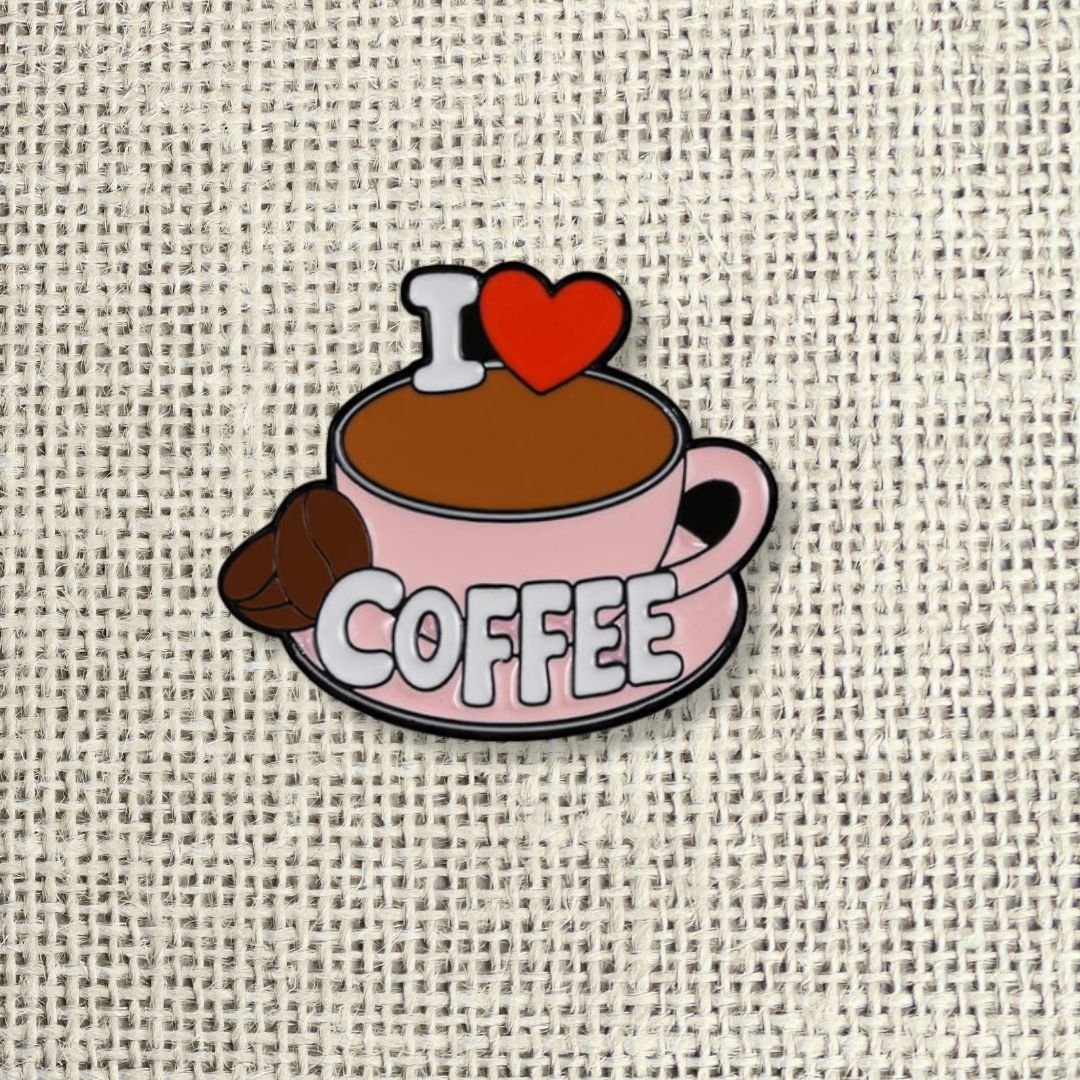 I Love Coffee enamel pin featuring a pink cup, brown coffee and a red heart.