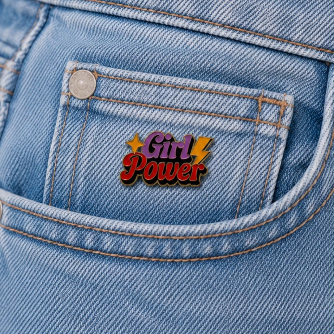 Girl Power enamel pin with colourful lettering and yellow star details on a blue denim pocket.