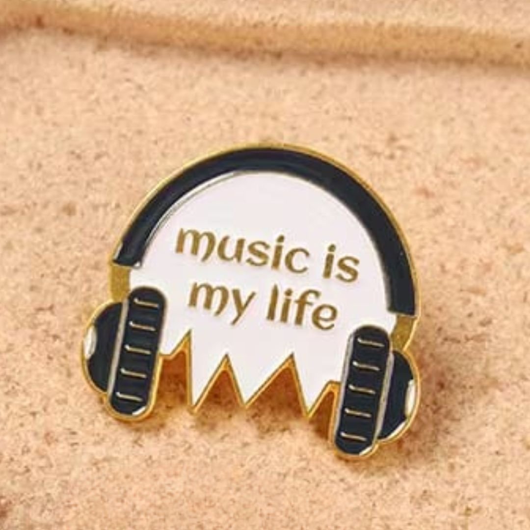 Music Is My Life enamel pin featuring black and yellow headphones, cream lettering and a musical waveform.