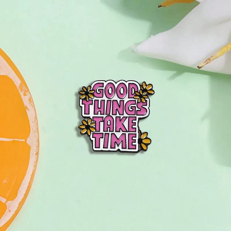 Good Things Take Time enamel pin with pink lettering and yellow flowers