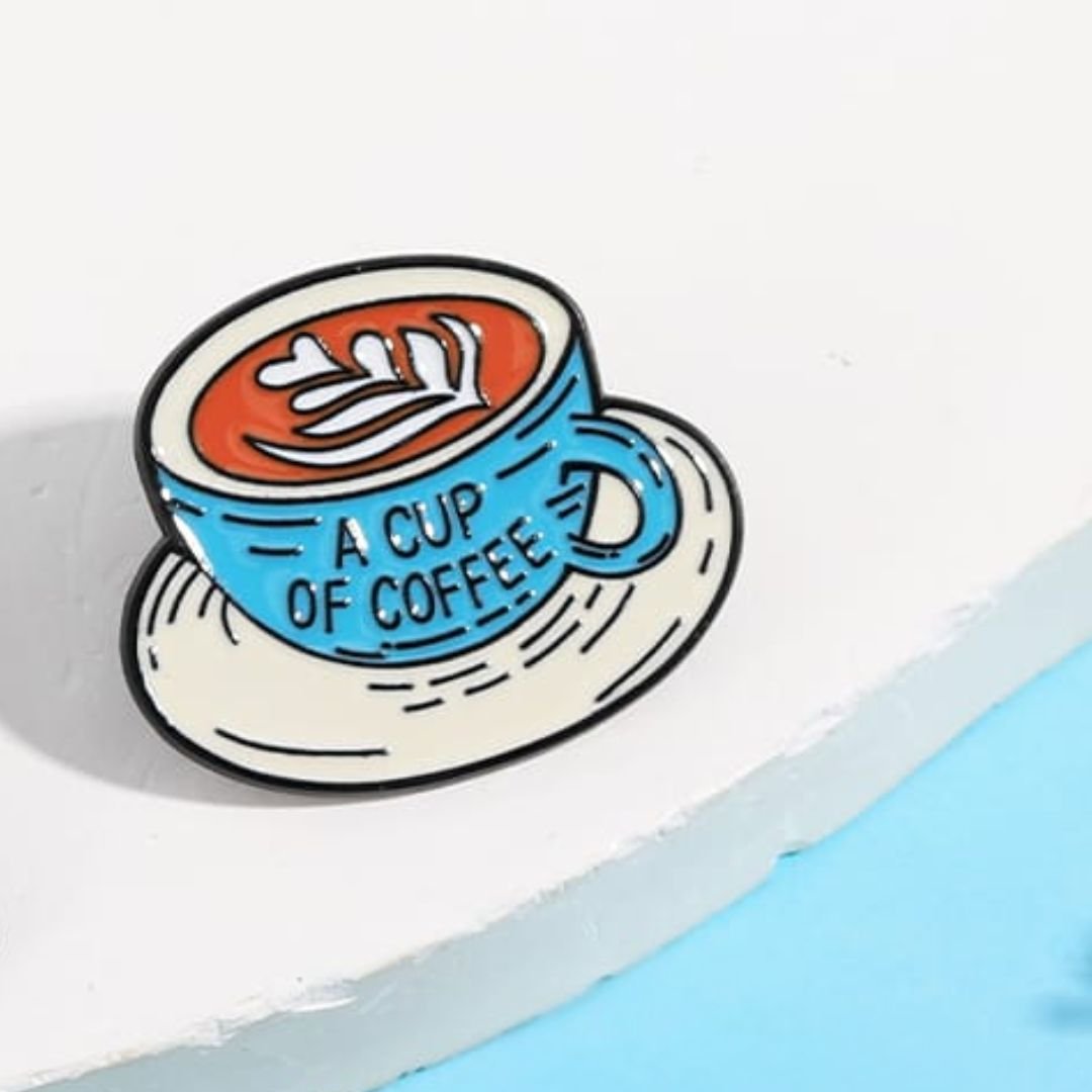 Blue coffee cup enamel pin with latte art and cream saucer illustration