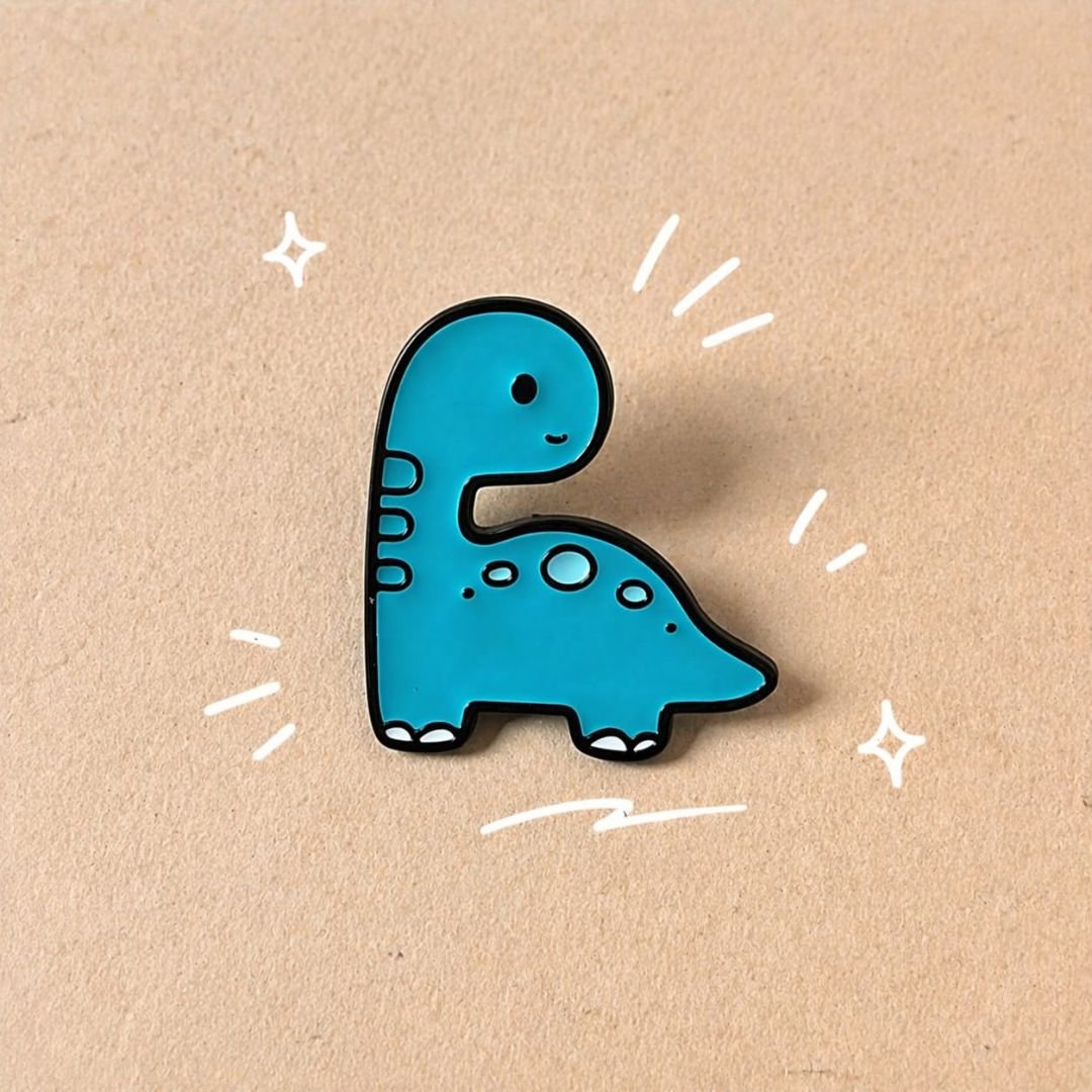 Turquoise-blue baby dinosaur pin with black outlines, measuring approximately 2.8 × 3.2 cm.