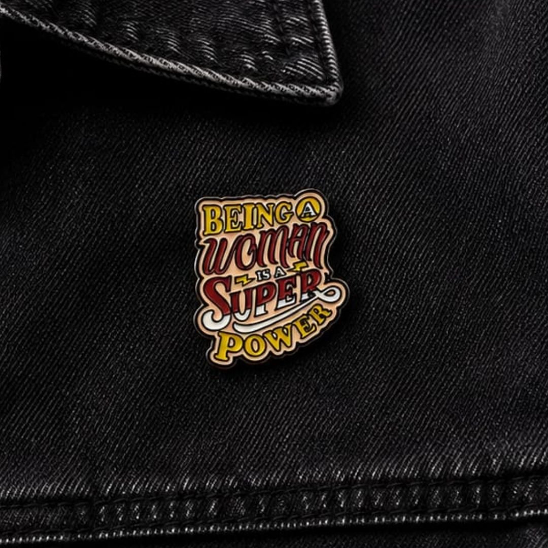 Being a Woman is a Superpower feminist enamel pin pinned on black denim jacket lifestyle photo