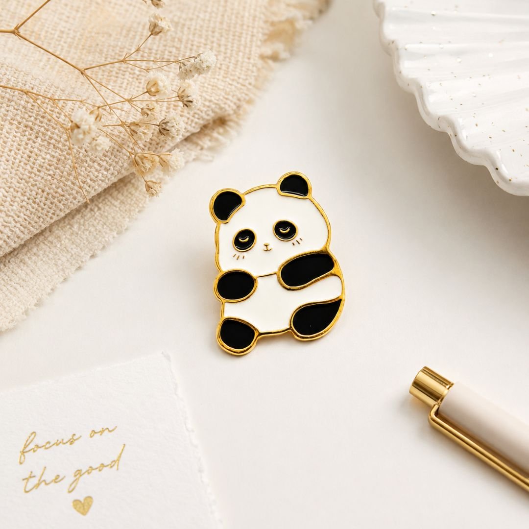 Cute black and white panda enamel pin with a gold-tone outline on a neutral background.