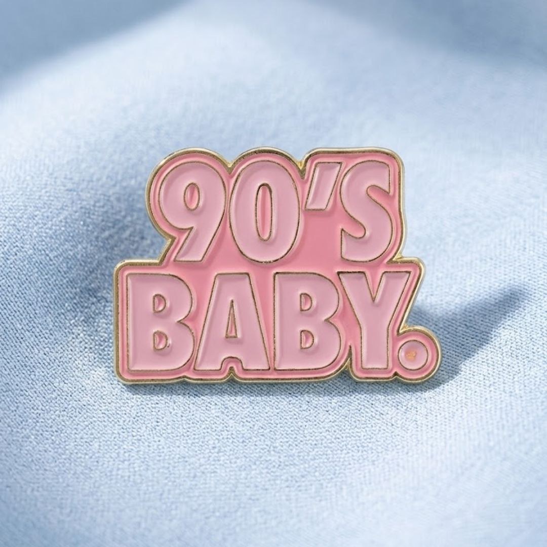 Pink 90s Baby enamel pin with light pink lettering and gold-tone outline.