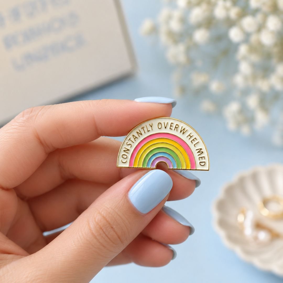 Constantly Overwhelmed rainbow enamel pin measuring 3.1 × 1.7 cm.