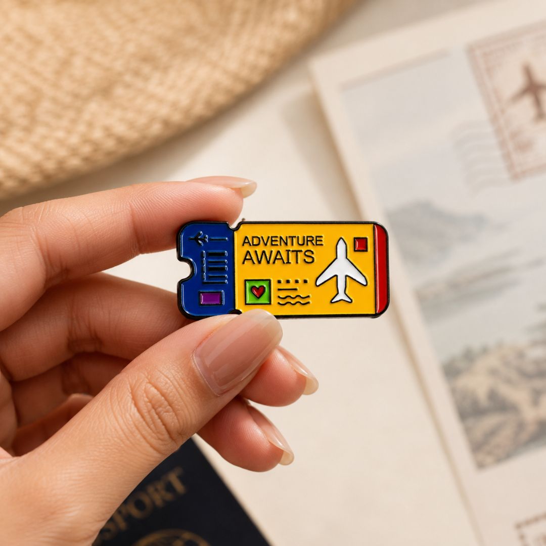 Colourful Adventure Awaits enamel pin featuring a white airplane and travel ticket design.