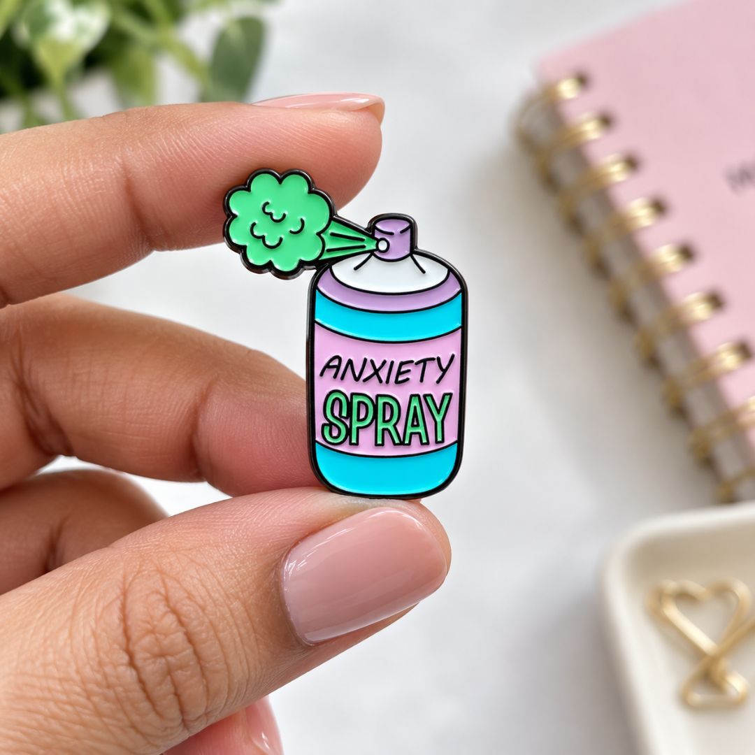 Colourful Anxiety Spray enamel pin featuring pink and turquoise bottle details, measuring 3 cm by 2.3 cm.